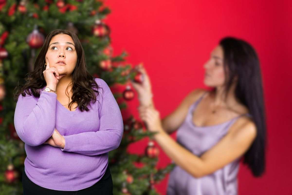 donna che addobba albero di natale e un'altra che pensa 