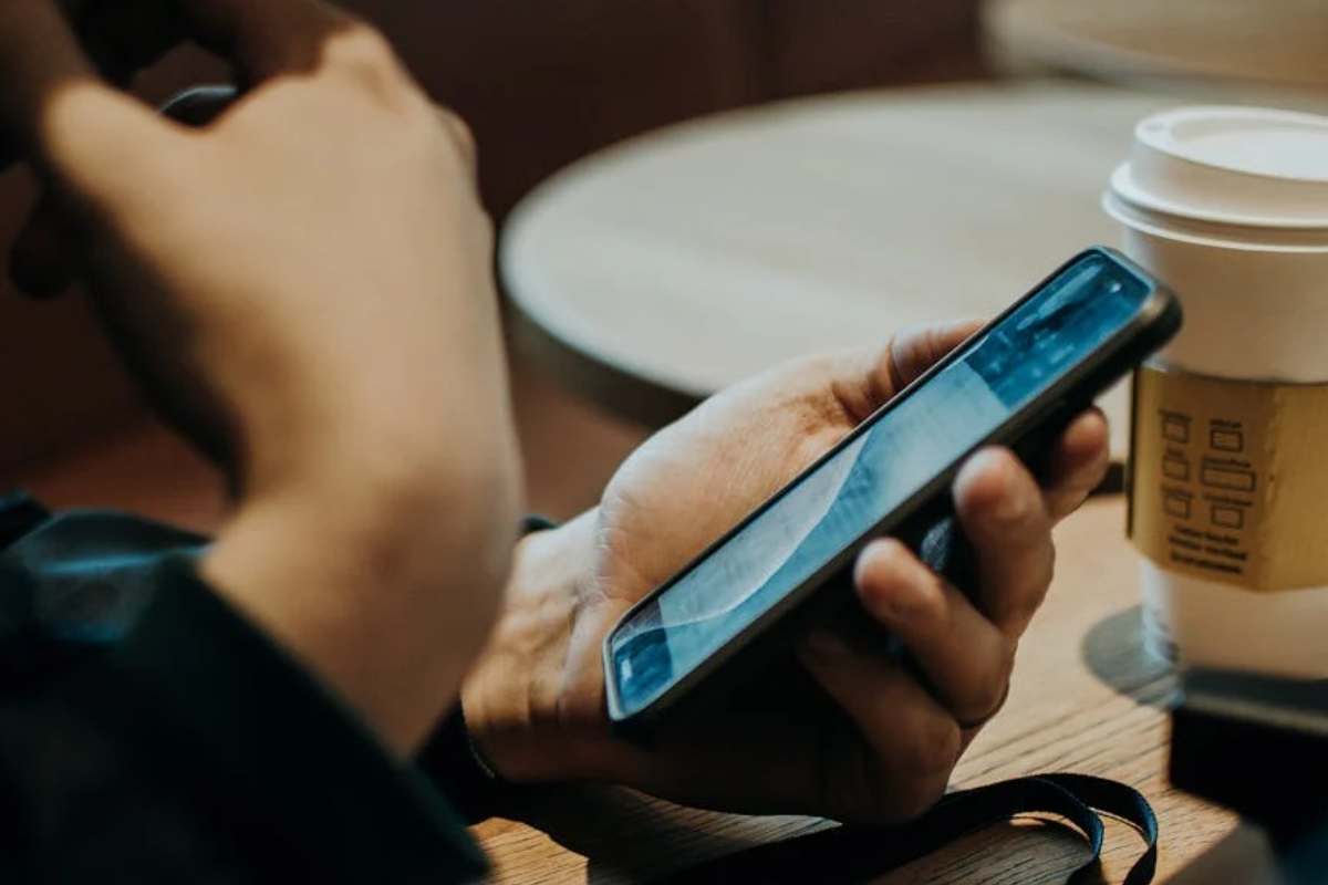 Una ragazza con un telefono in mano e un bicchiere di caffè sul tavolo